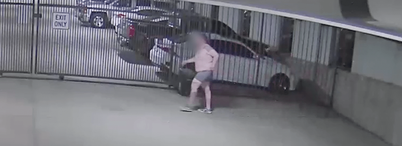 Shirtless Trespasser Climbing Parking Garage Gate Hero