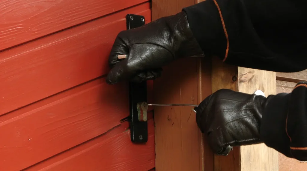 person wearing black gloves trying to pick a lock