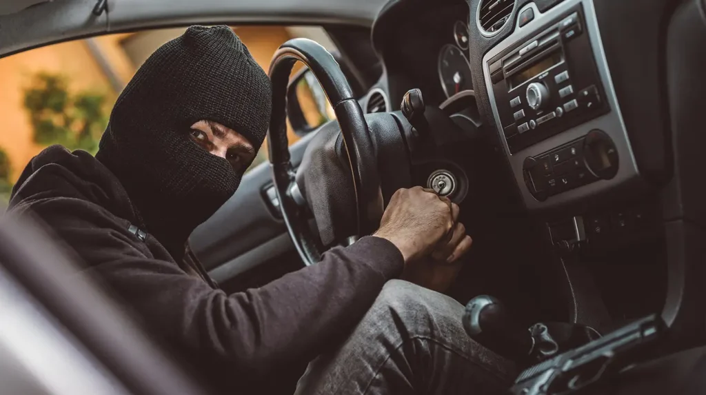 Masked person sticking something into a car's ignition